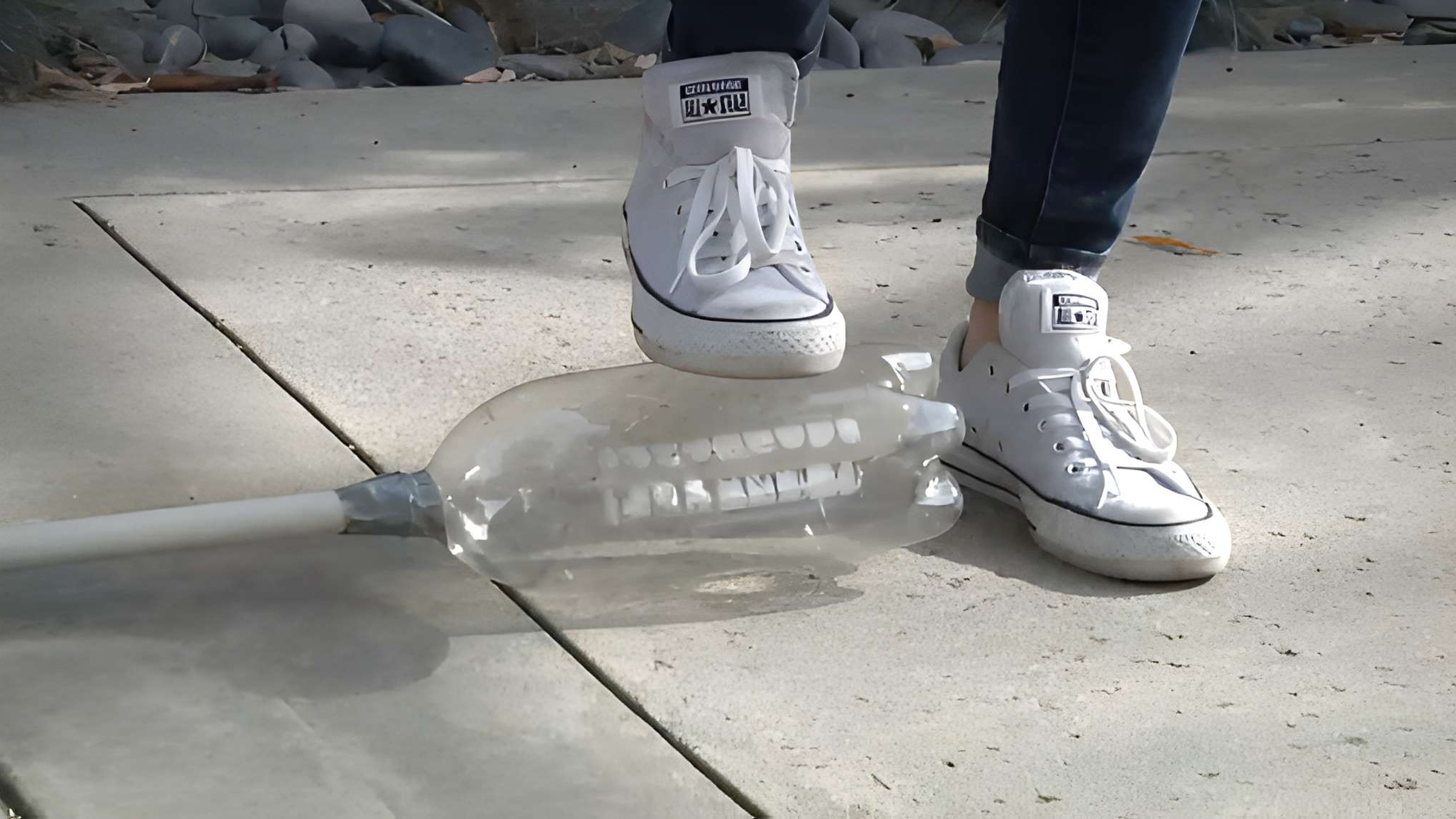 A foot on top of a plastic bottle, part of a homemade stomp rocket.