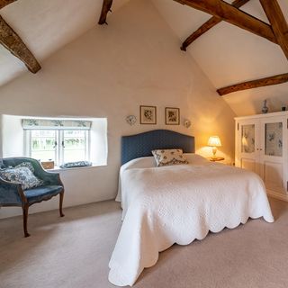 bedroom with and vaulted ceiling and white wall and arm chair