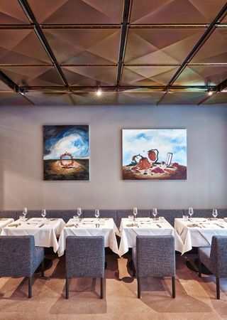 Restaurant with tables, chairs, wall paintings and mirror ceilings.