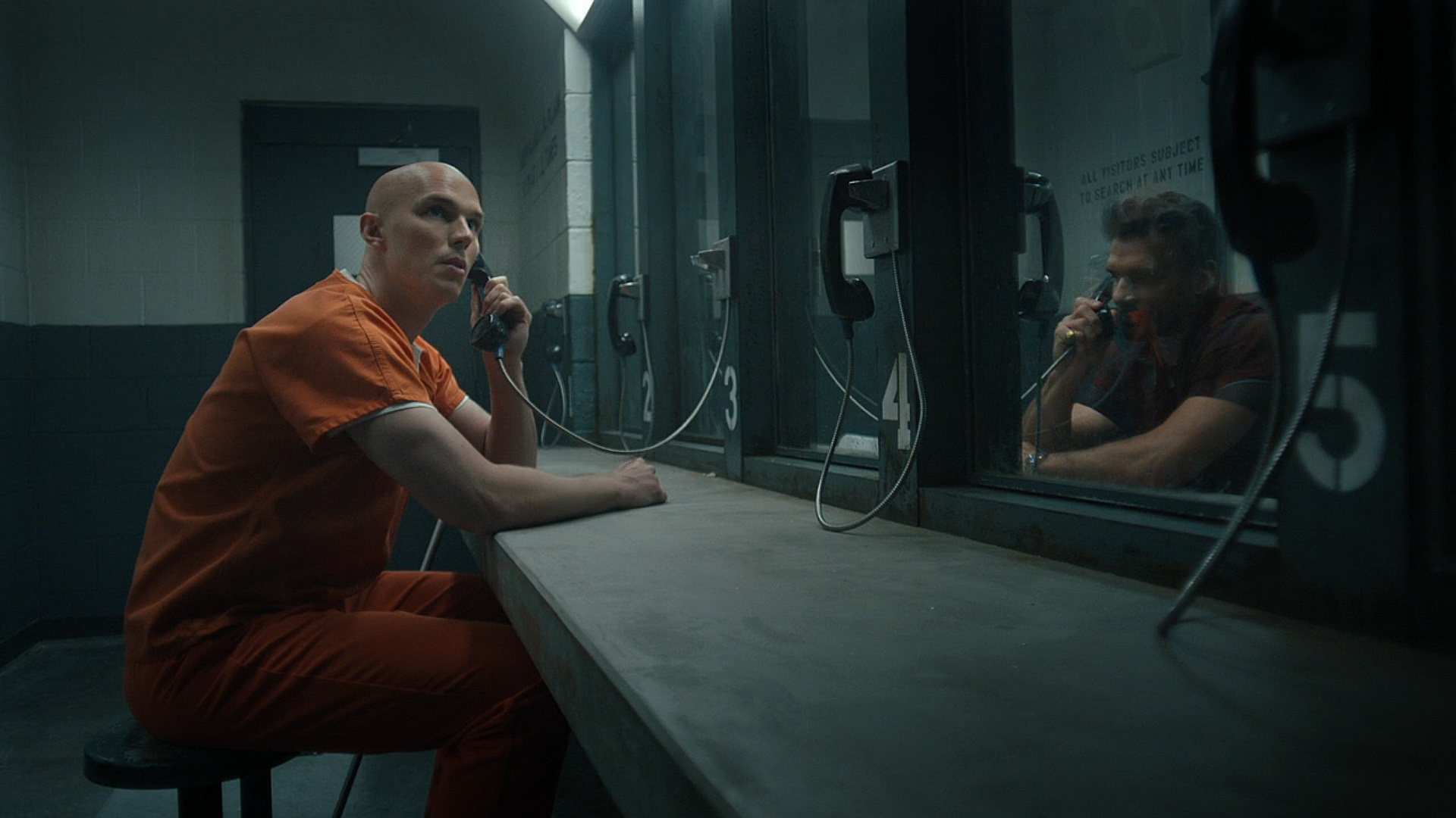 Lex Luthor looking around while speaking to Rick Flag Sr via a prison telephone in Peacemaker season 2 episode 6