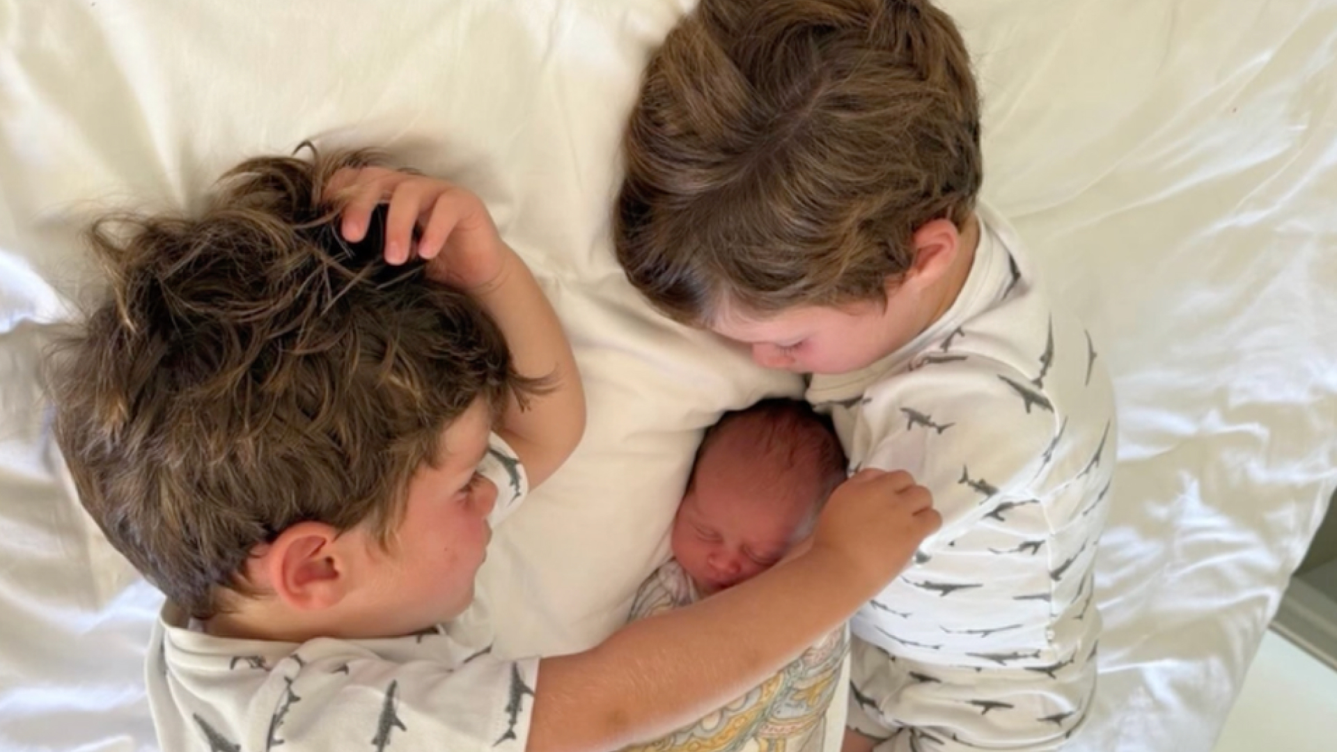 Princess Eugenie's three children wearing pajamas on a bed