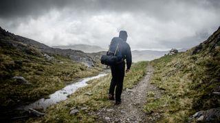 A hiker walking along a trail in the rain