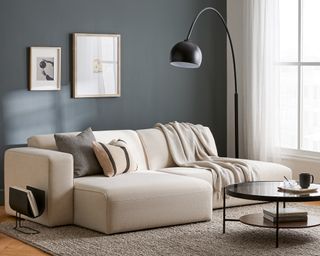 Beige couch in dark blue living room with gray rug