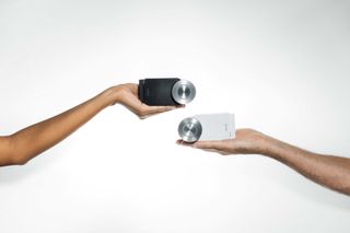 Two Nuki Smart Locks in black and white being held by hands