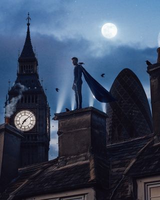 Winged superhero standing on a building overlooking the London skyline