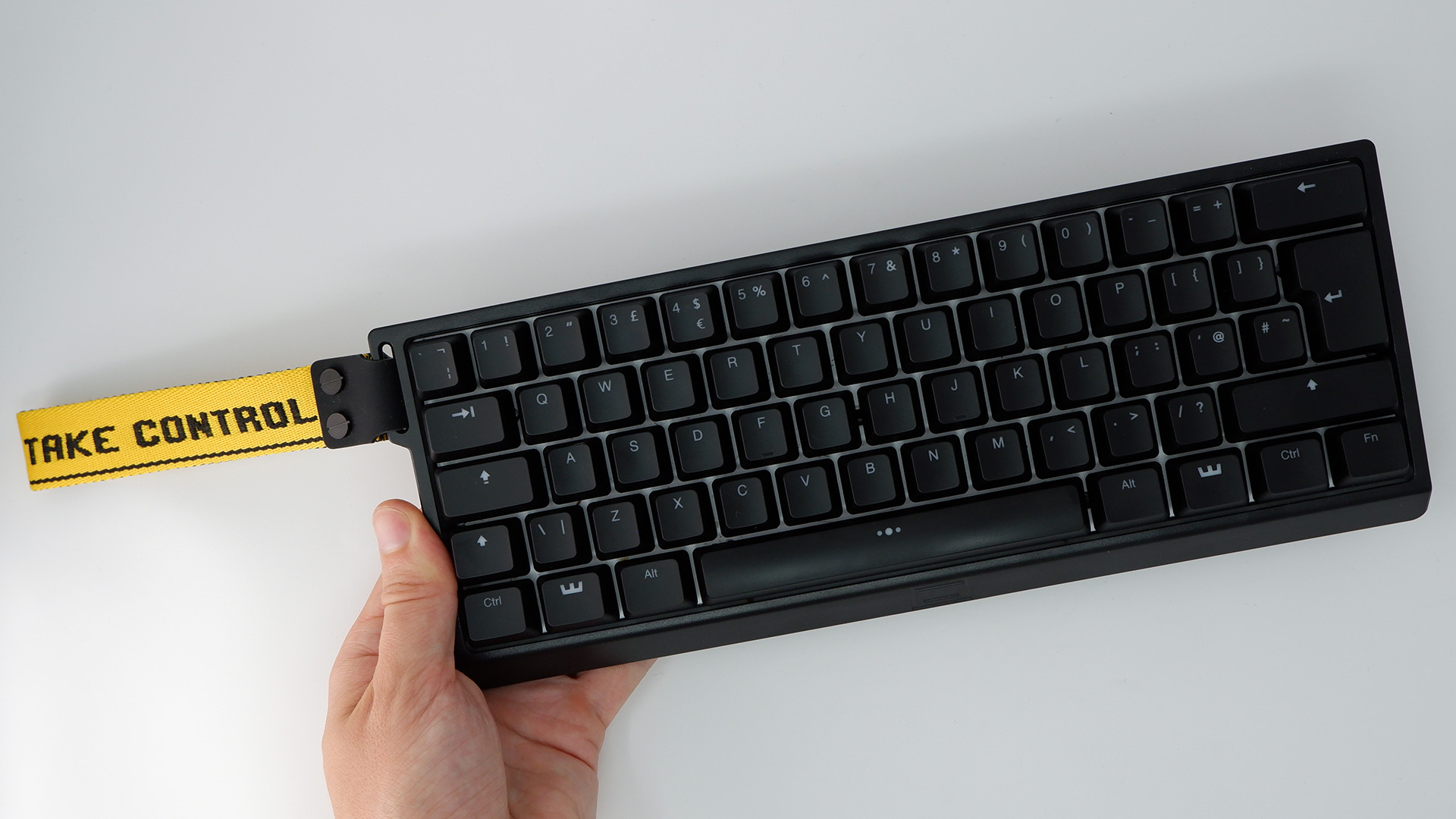Wooting 60HE gaming keyboard pictured with yellow wrist strap attached.