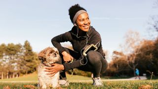 woman in active gear crouching next to her dog