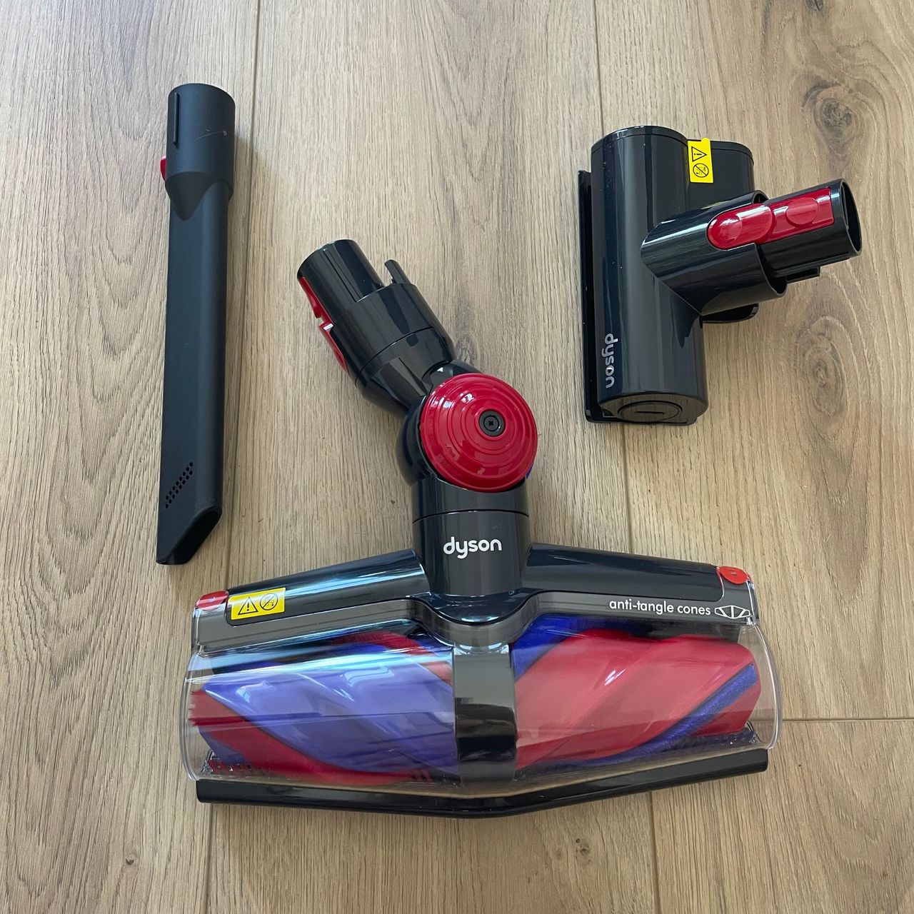 Floorhead and tools of the Dyson V10 Konical vacuum laid out on wood-effect flooring