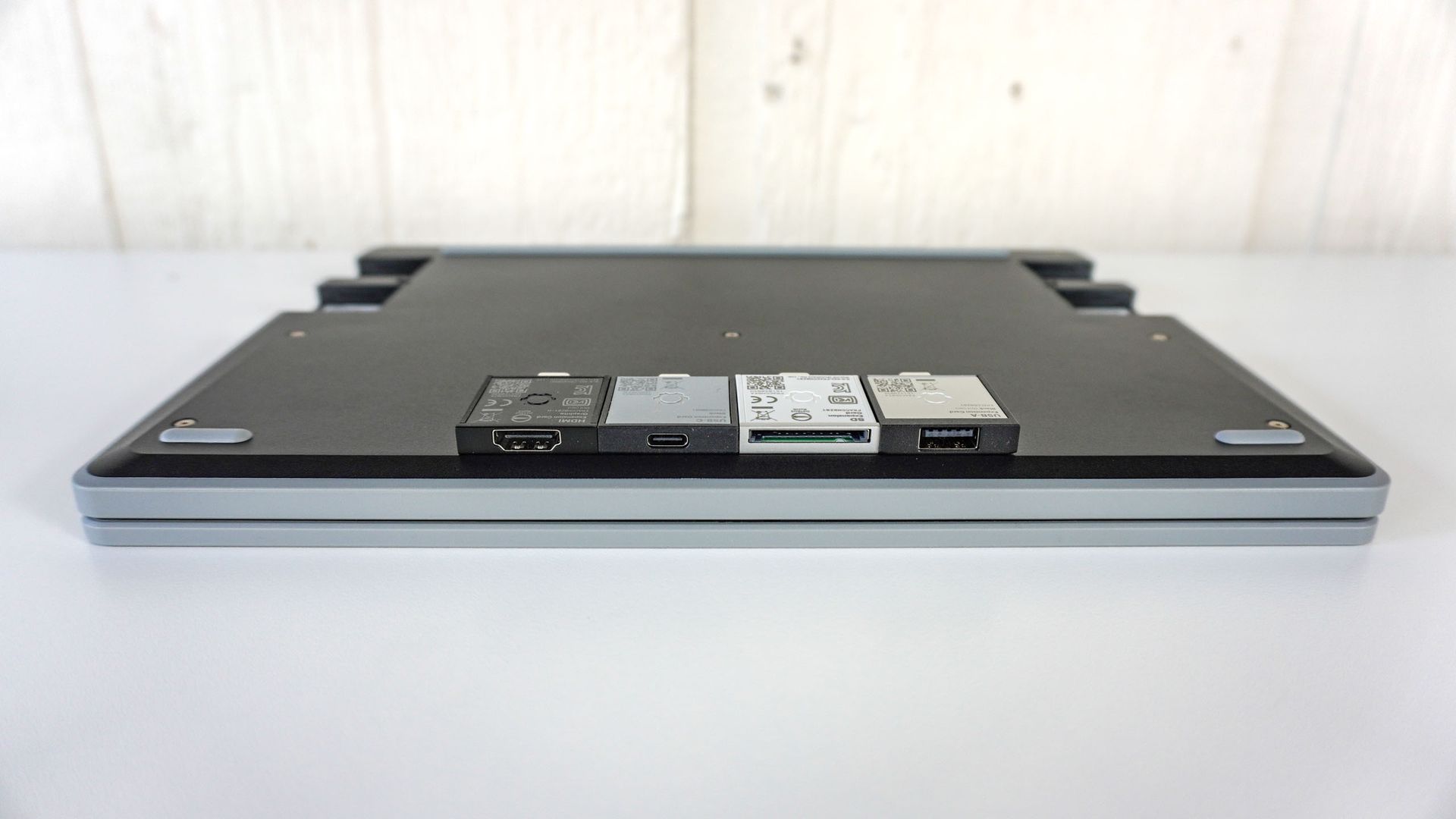 The Framework Laptop 12 lying flat upside down on a table with four Expansion Cards on top of it