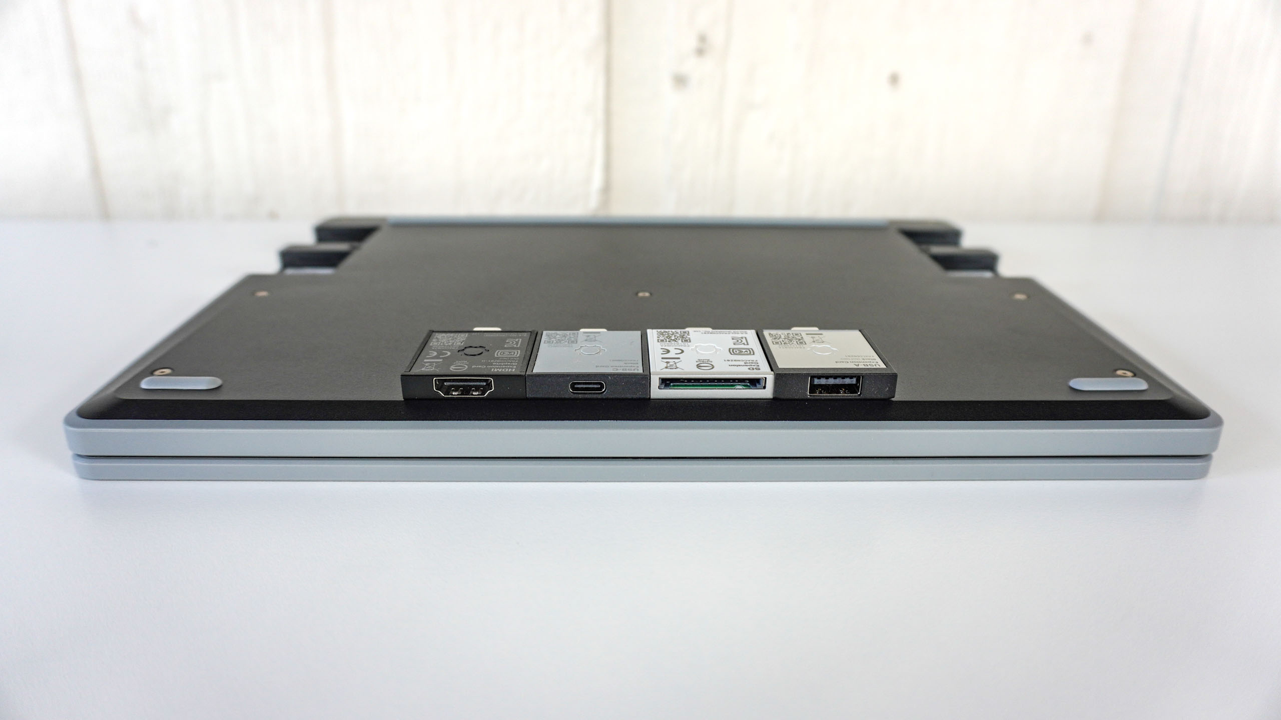 The Framework Laptop 12 lying flat upside down on a table with four Expansion Cards on top of it