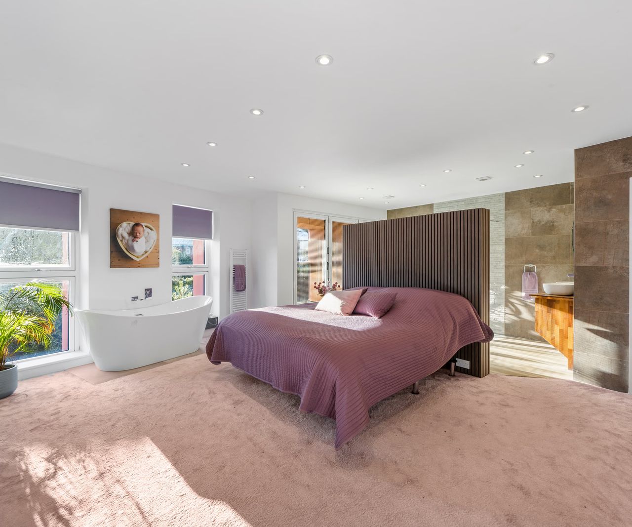 A master bedroom with a bath inside and a room divider