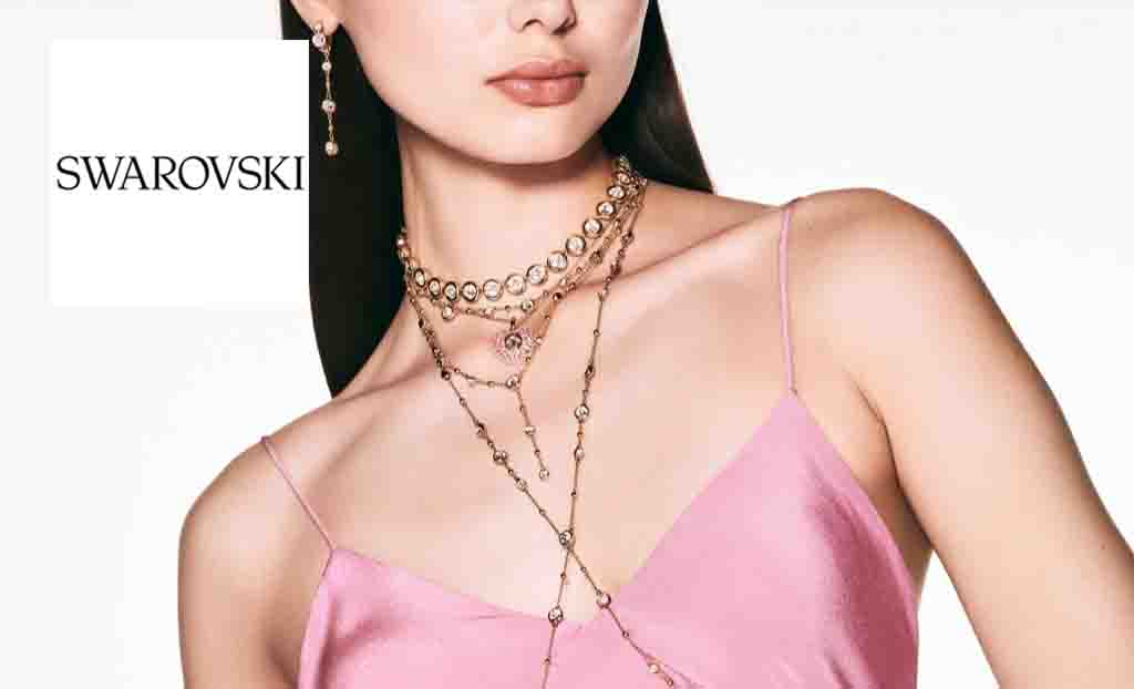swarovski logo placed over a close up shot of a womans neck showcasing her necklaces