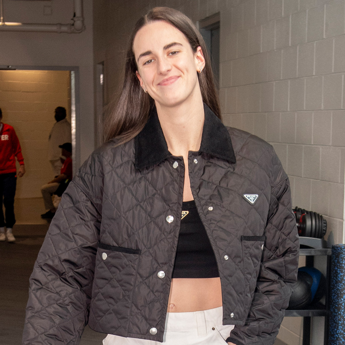 Caitlin Clark #22 of the Indiana Fever arrives to the arena before the game against the Chicago Sky during the preseason game against the on August 30, 2024 at the Wintrust Arena in Chicago, IL. She's wearing a brown Prada quilted coat, white carpenter jeans, and a black Prada bralette.