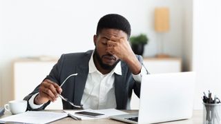 Men sitting at computer looking stressed