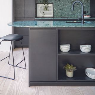 Black kitchen with an island that has open shelving.