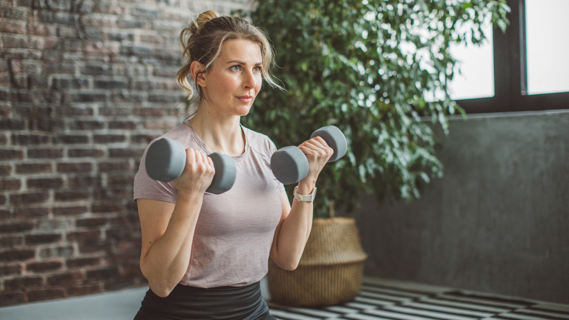 Woman doing arm workout with dumbbells at home