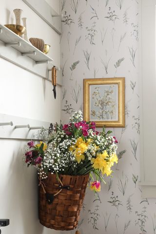 Delicate leaved wallpaper with flowers in indoor hanging basket and peg shelf storage painted in white