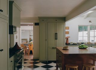 a sage green kitchen with a black and white checkerboard floor