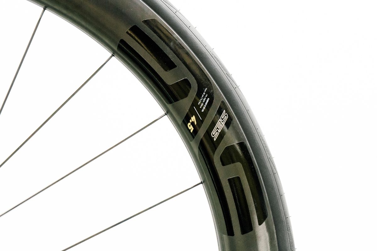 An aero road wheel stands against a white wall