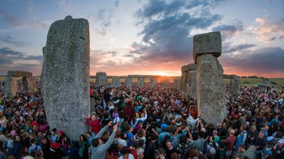 Crowds gathering round Stonehenge as dawn breaks on the summer solstice