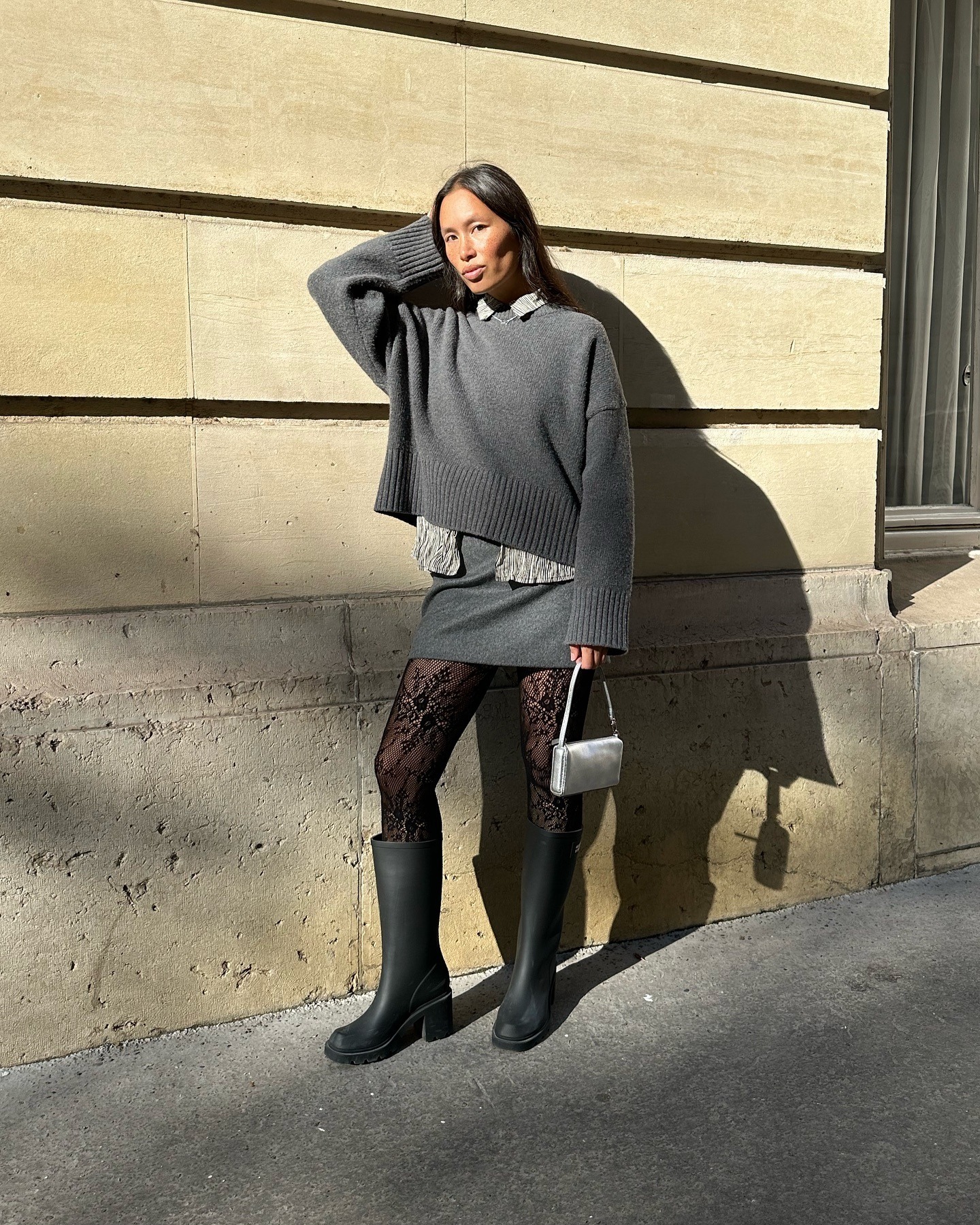 Influencer @vikilefevre wears a grey miniskirt with knee-high boots and a grey jumper.