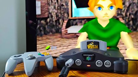 Close up of HDMI modded N64 on woodgrain coffee table with Zelda: Ocarina of Time gameplay on TV in backdrop.