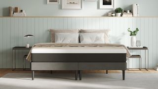 The Emma Original Mattress placed on a grey fabric bed base and dressed with white and yellow striped sheets