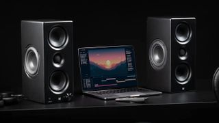 Monolith MTM 100 speakers with laptop on black background