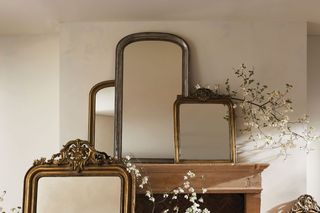 A fireplace mantle decorated with layered mirrors