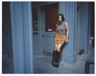 Actress Lukita Maxwell, leaning against a blue building.