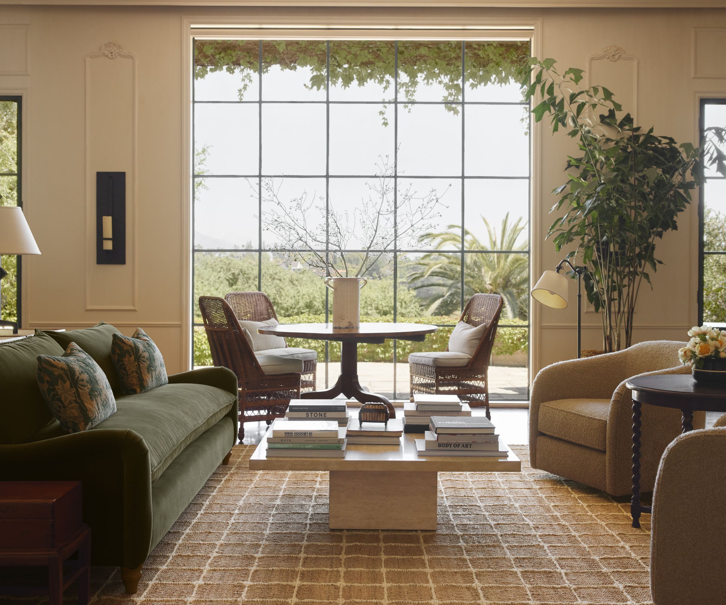 A neutral living room with a grid rug and green sofa