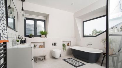 A modern bathroom vanity with black framed mirror and black metal heated towel rail with geometric-patterned towel decor and houseplant