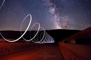A Perseid meteor crosses the night sky beside the Milky Way above a walkway at Lyman Run State Park