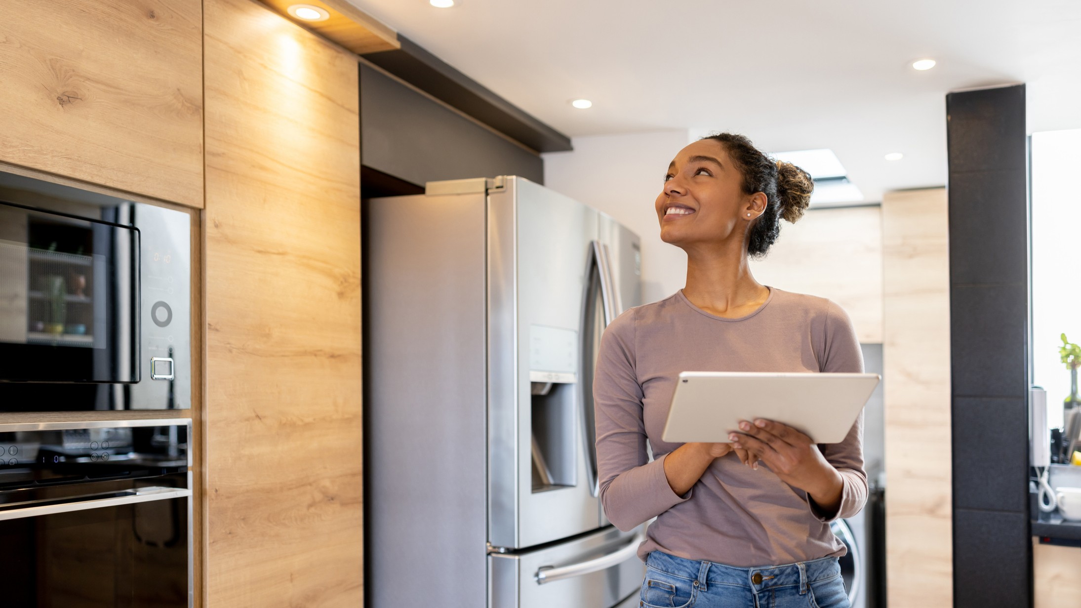Woman using tablet to control smart home devices in kitchen