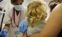 A child being held by her mother prepares to get a vaccine at a doctor's office