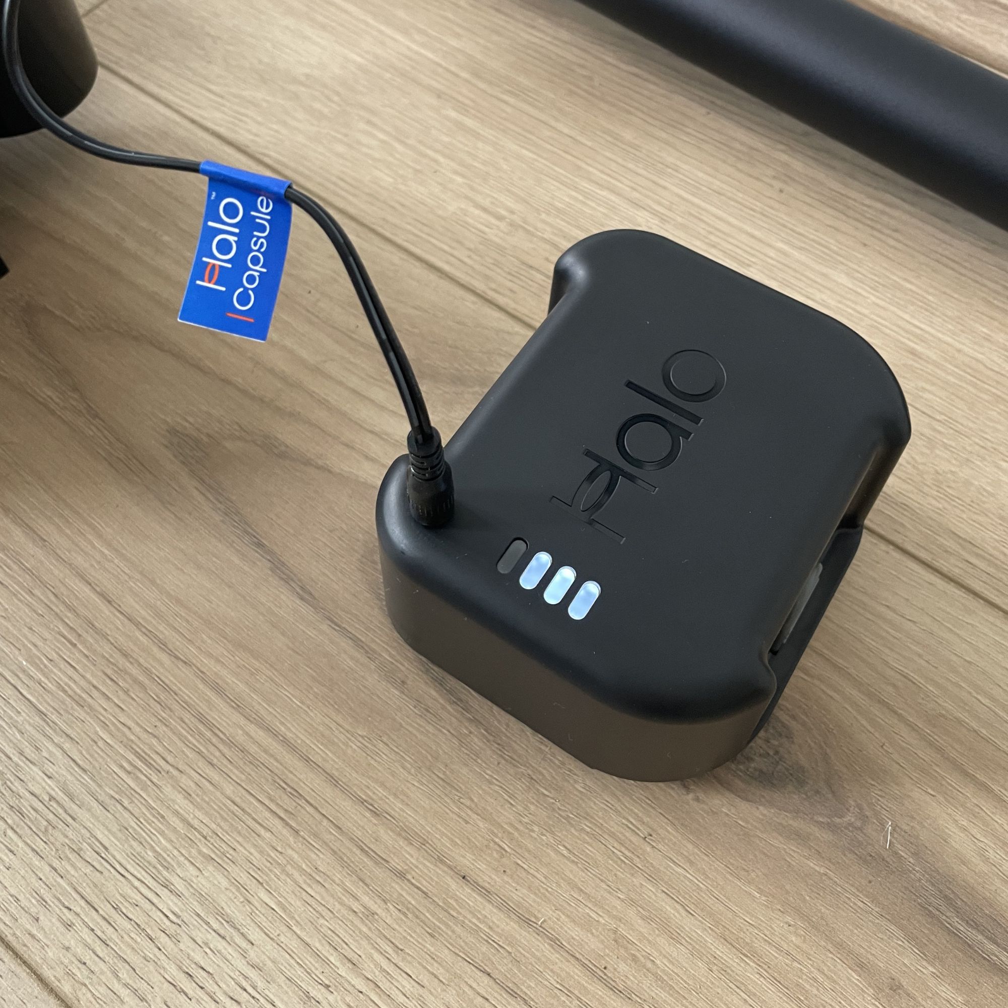 Battery of the Halo Capsule XR charging on wood-effect flooring