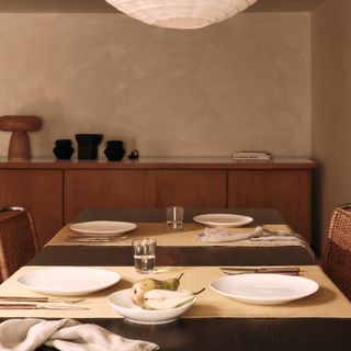 A set dinner table in a dining room with beige limewash walls