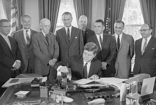 President Kennedy signs a Social Security Bill in the Oval Office