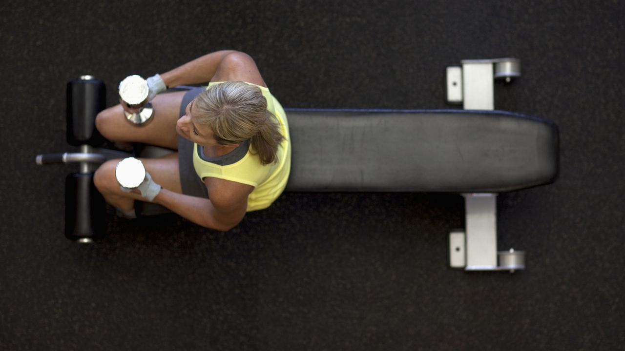 Best weight bench workouts: pictured here, a woman pauses while working out with free weights on a bench.