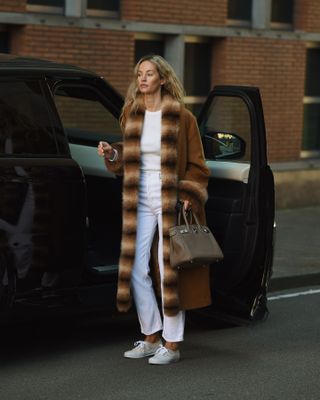 Woman in white jeans and camel coat.