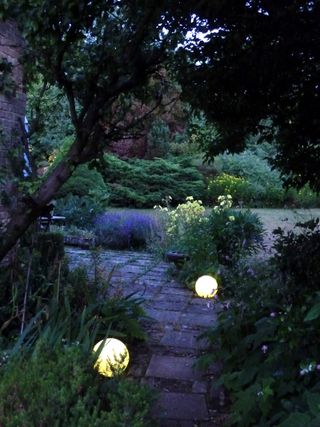 Stone Globe Lights path lighting in a large garden with a stone path, and a lake in the background