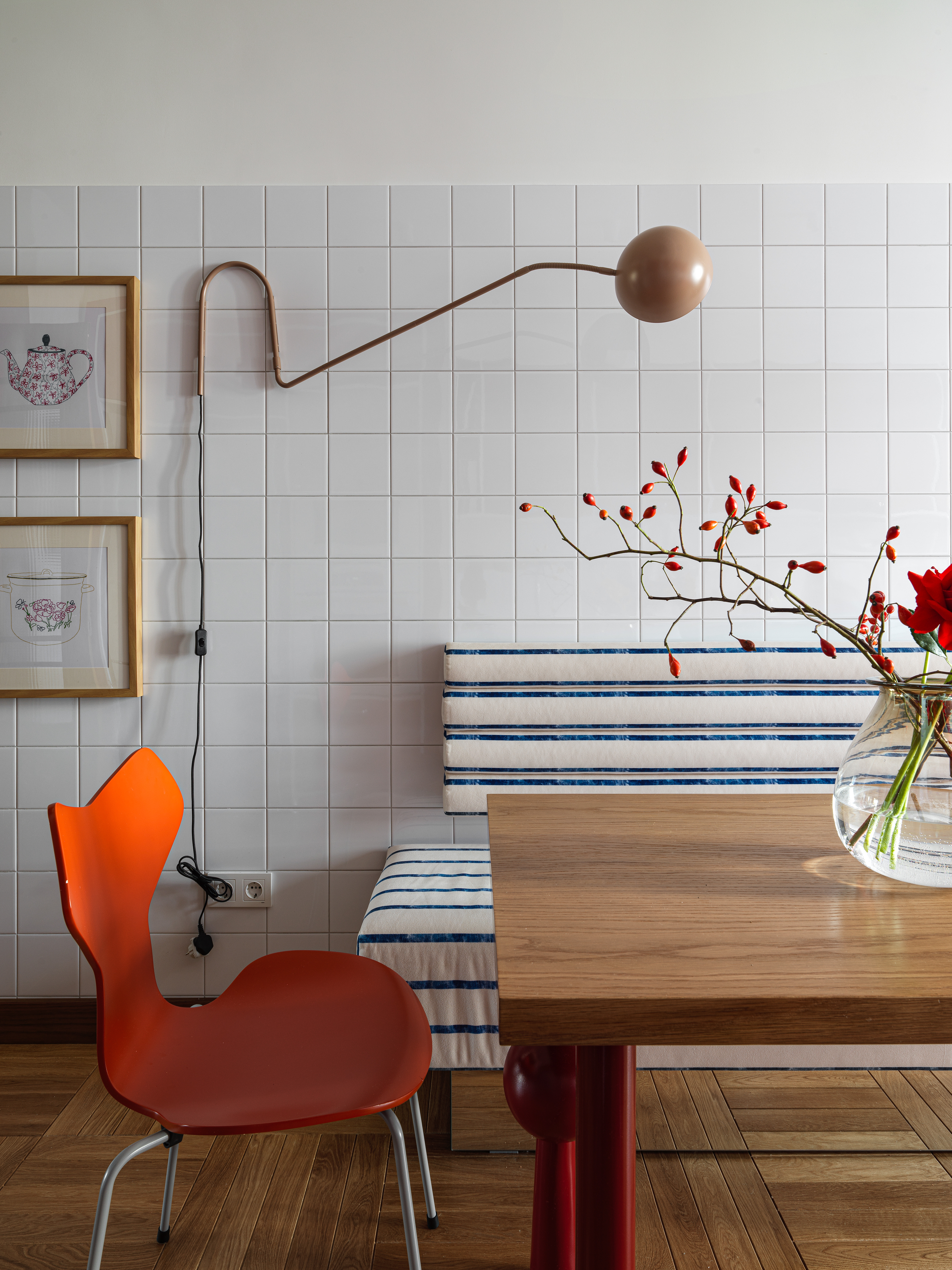 A small dining space with a red chair, built-in seating, and a brown wall lamp