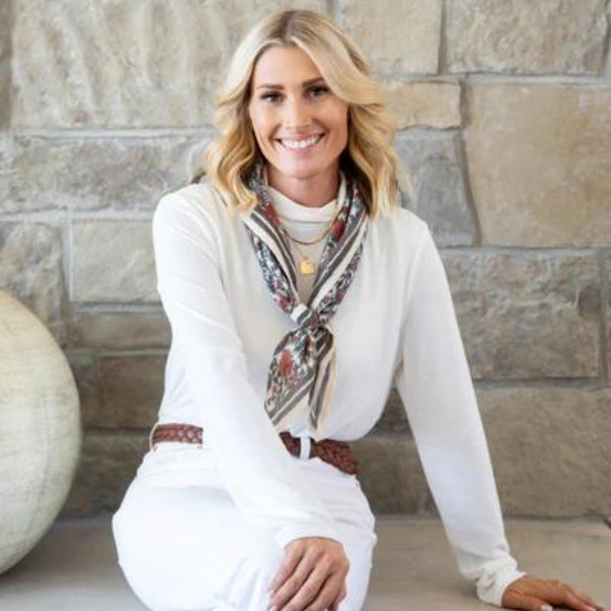 Kirsten Krason, Co-owner and principal designer at House of Jade Interiors, a white woman with blond hair wearing white clothing wth brown belt and printed silk scarf