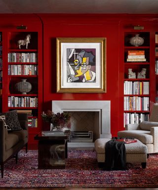 formal lounge with bright red wall, built-in shelves, dark red patterned rug and gold framed abstract artwork