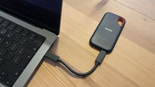 Sandisk Extreme Portable SSD V2 on a wooden table connected to a laptop