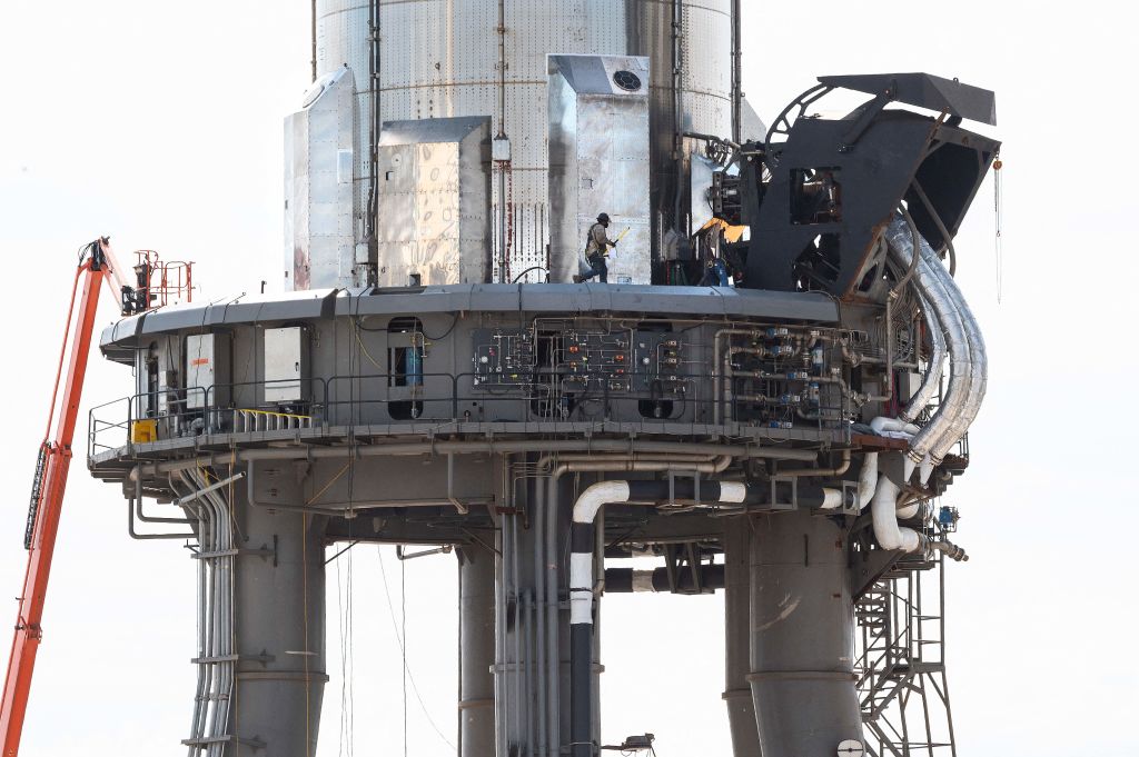 A man walks across the platform holding SpaceX's first orbital Starship SN20 stacked atop its massive Super Heavy Booster 4 at the company's Starbase facility near Boca Chica Village in South Texas on Feb. 10, 2022.