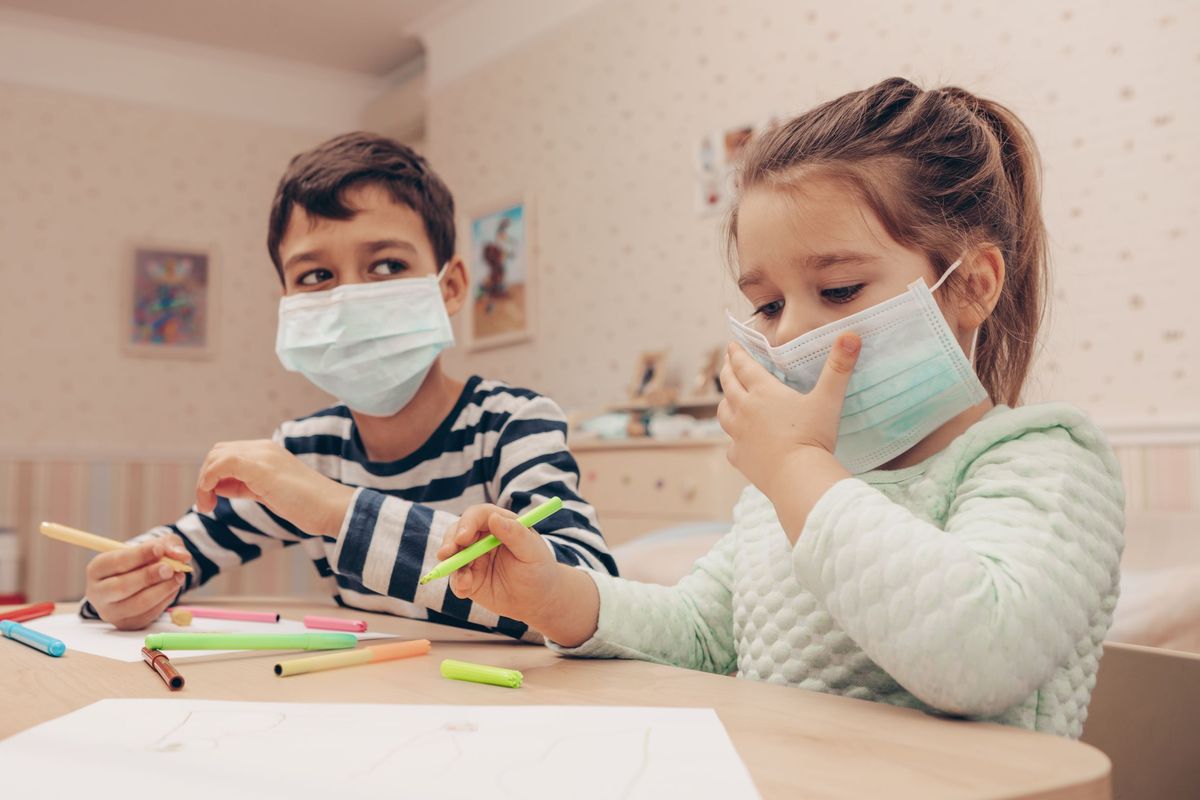 Children wearing masks while playing inside.