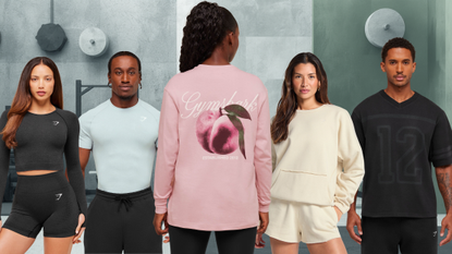 Five models wearing gymshark clothing stand in a gym setting. The model in the center of the image is facing the wall so the gymshark branding can be seen on her back.