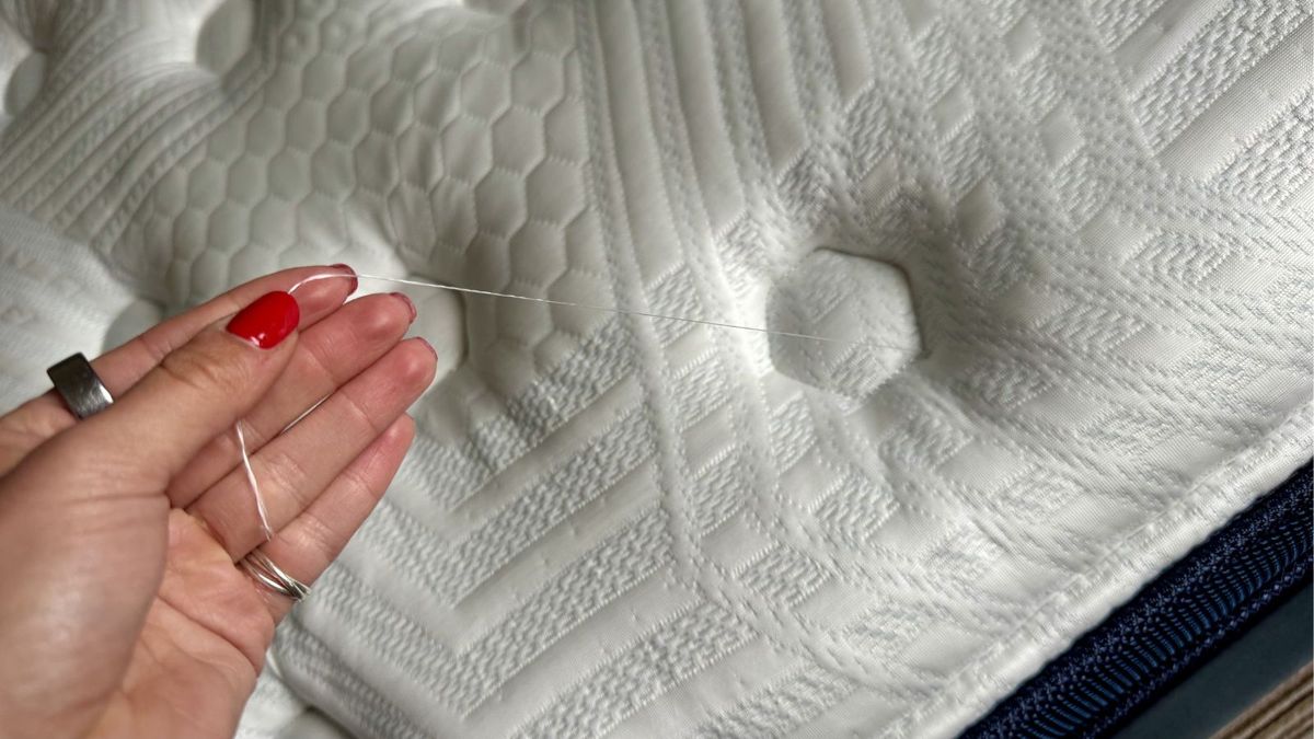 Our mattress tester holding a loose thread on white cover of Brooklyn Bedding Thermobalance LX Elite mattress