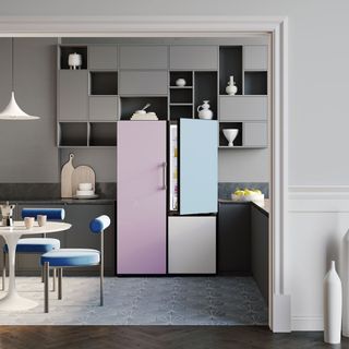 a grey kitchen with dark wooden floors and a fridge with three tone pastel scheme - pink, blue and cream